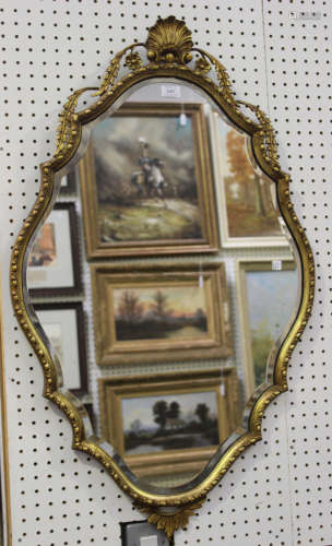 A late 20th century Italianate gilt framed wall mirror of shaped outline, 102cm x 62cm.Buyer’s