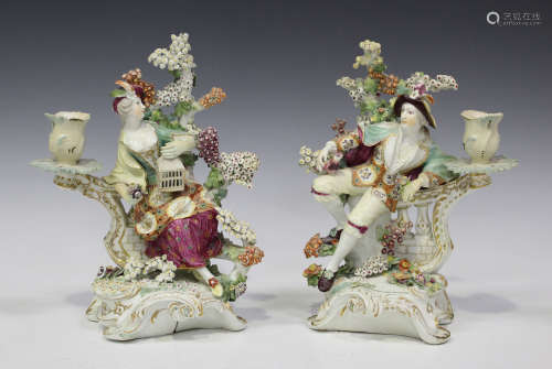 A pair of Derby porcelain figural candlesticks, late 18th century, each modelled as a seated lady or