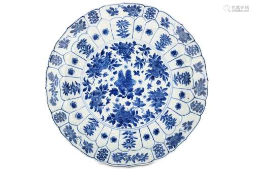 A CHINESE BLUE AND WHITE ‘PEONIES’ MOULDED DISH. Kangxi mark and of the period. Decorated with a central roundel enclosing floral bouquets, enclosed within a border of moulded lappets each enclosing a single flower, within a further band of