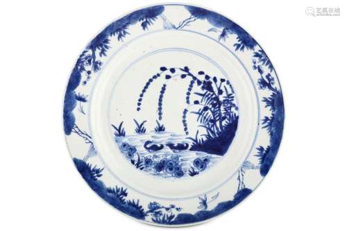 A CHINESE BLUE AND WHITE ‘MANDARIN DUCKS’ DISH. Kangxi mark and of the period. Painted with a central roundel with a pair of ducks swimming on a pond below overhanging flowering branches, within a border of flowers and grassy foliage, six