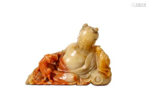 A CHINESE SOAPSTONE CARVING OF A RECLINING IMMORTAL. Kangxi. The figure seated against a cushion in long flowing robes the chest bare, the bearded figure with the hair drawn up in two topknots, a small lion cub clambering over his legs, 18cm H.