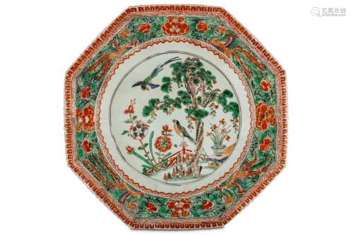 A CHINESE FAMILLE VERTE OCTAGONAL ‘BIRDS’ DISH. Kangxi. The central roundel with two birds beside a pine tree within a garden, enclosed in a band of phoenixes among peonies on a green stipple ground, within smaller iron red ruyi head, lappet and