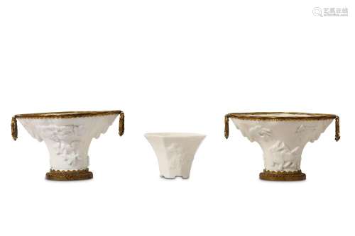 A PAIR OF CHINESE BLANC DE CHINE LIBATION CUPS. Kangxi. Each moulded to resemble the truncated tapering form of a rhinoceros horn libation cup, moulded with various animals below overhanging rockwork, with European gilt bronze mounts, together with