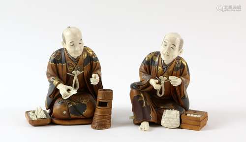 Pair of carved wood and ivory okimono of seated figures of men in gilded robes, one a florist, the