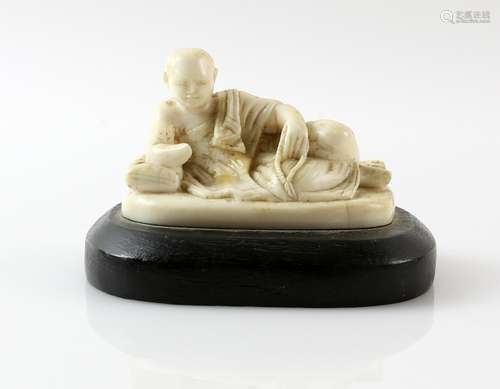 Early 20th century Chinese carved ivory figure of a man reclining, on wooden base, figure 6.5cm