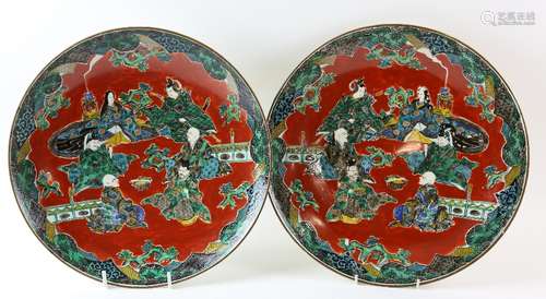 Pair of Chinese porcelain chargers decorated with six seated figures in an outdoor setting, mark