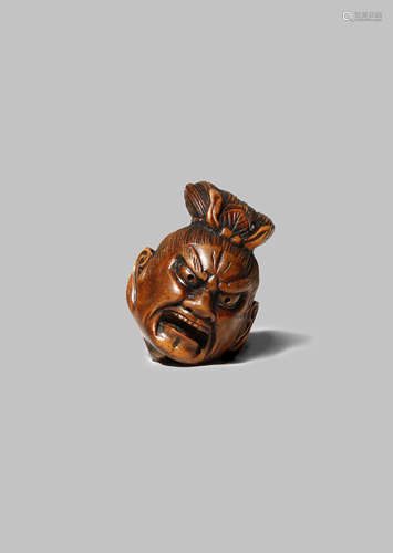 A JAPANESE WOOD NETSUKE MEIJI 1868-1912 Carved as the severed head of a Nio, the Buddhist guardian