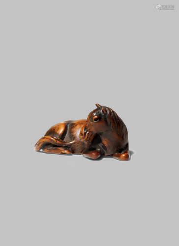 A JAPANESE WOOD NETSUKE OF A HORSE EDO/MEIJI PERIOD Lying with its head turned to the side and the