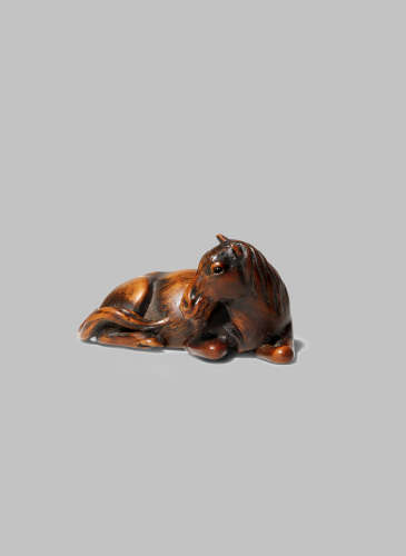 A JAPANESE WOOD NETSUKE OF A HORSE EDO/MEIJI PERIOD Lying with its head turned to the side and the
