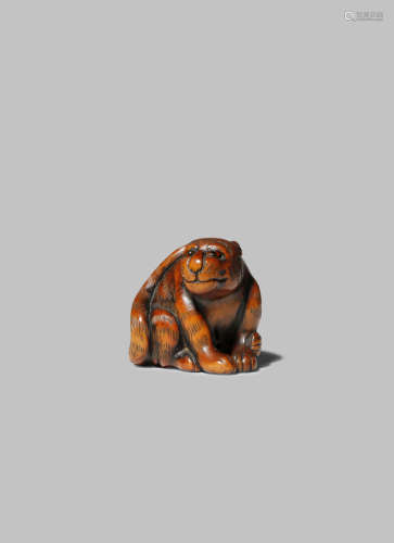 A JAPANESE WOOD NETSUKE OF A TIGER EDO/MEIJI PERIOD The feline seated on his haunches, its long tail
