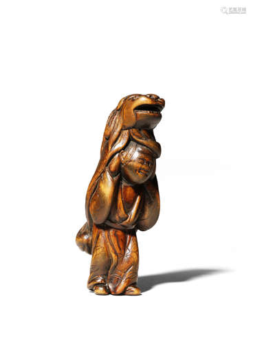 A JAPANESE WOOD NETSUKE OF A KARAKO EDO 1603-1868 The tall boy smiling and holding a lion mask above