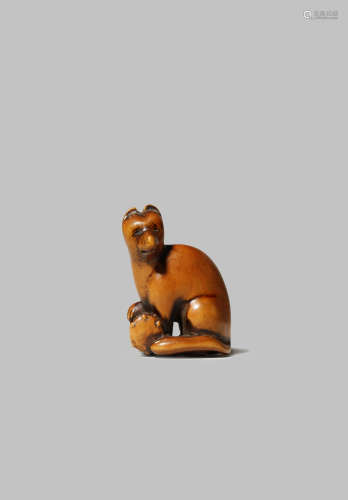 A JAPANESE WOOD NETSUKE EDO 1603-1868 Carved as a fox seated with its right paw resting on a tsuzumi