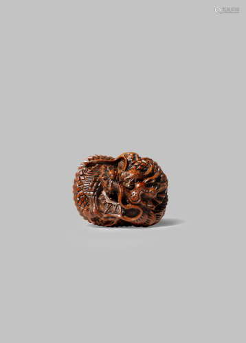A JAPANESE WOOD NETSUKE OF A DRAGON MEIJI 1868-1912 The mythical beast tightly coiled and holding