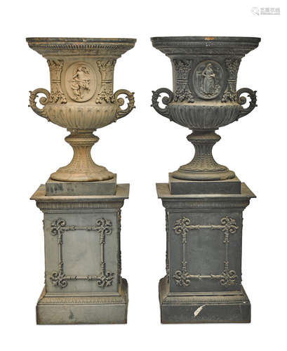 A pair of large Neoclassical style painted cast iron urns on pedestals