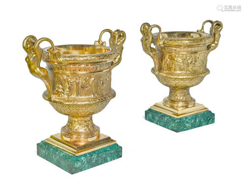 A pair of Neoclassical style gilt bronze two handled urns on malachite veneered plinths