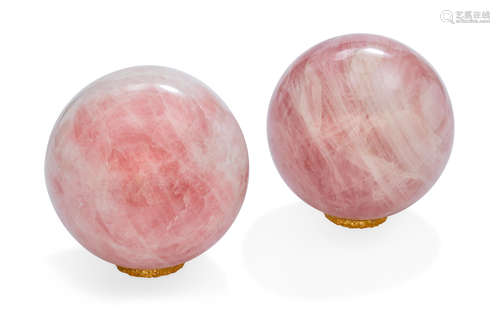 A pair of rose quartz orbs each raised on gilt bronze wreath stand