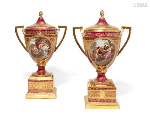 Early 20th century A pair of Vienna style porcelain two handled covered urns on attached plinths