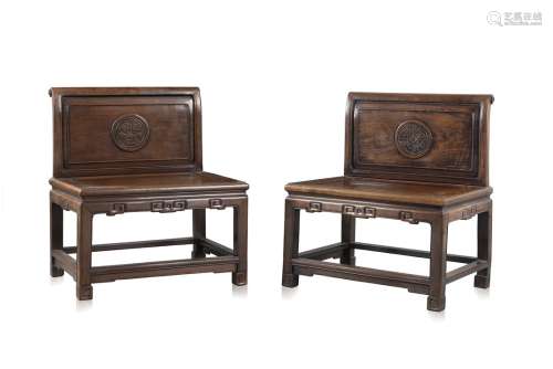 A pair of rosewood chairs with carved circular designs on the back and key fret along the front