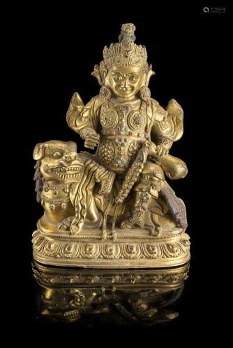 A gilt bronze model of a deity seated on a Buddhist lion on a lotus base, wearing an armor with