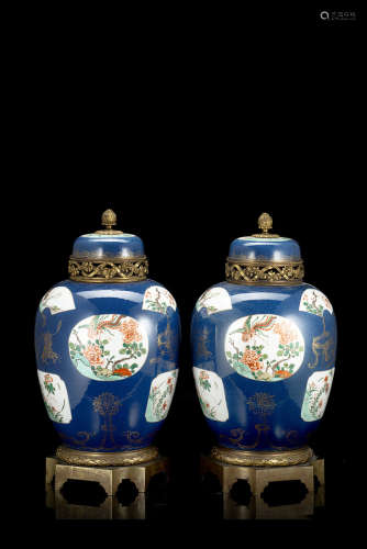 A pair of ginger jars and cover decorated with Famille Verte floral motifs in panels and gilt