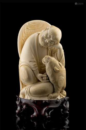 An ivory model of a seated monk accompanied by a tigerChina, early 20th century(h. 19.5 cm.)