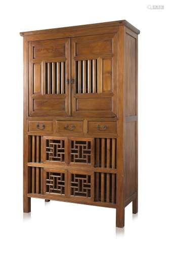An elm wood kitchen cabinet with open slat doors and three drawers above a carved and pierced