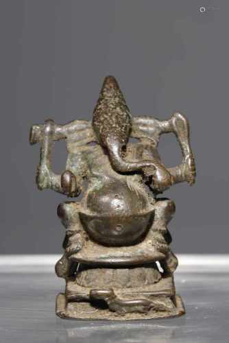 GANESHAbronze,India, 16th century,H: 7,5 cmVotive sculpture of Ganesha seated on elaborate 8-pointed