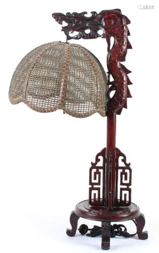 CHINESE CARVED WOOD DRAGON TABLE LAMP - Carved dragon head surmounts a serpentine pole anchored by openwork brackets on a round foot...