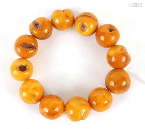YELLOW BEESWAX BEAD BRACELET - Twelve large polished russet-yellow beads, each with an irregular dimple on the surface