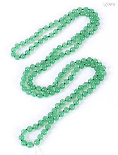 LONG NECKLACE OF GREEN HARDSTONE BEADS - Comprising an endless loop of 7 mm green translucent beads knotted on a black cord
