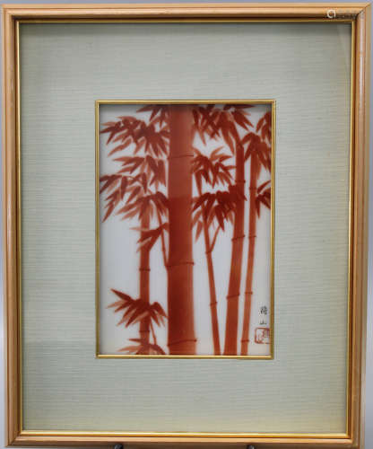 A framed Japanese porcelain plaque with red bamboo