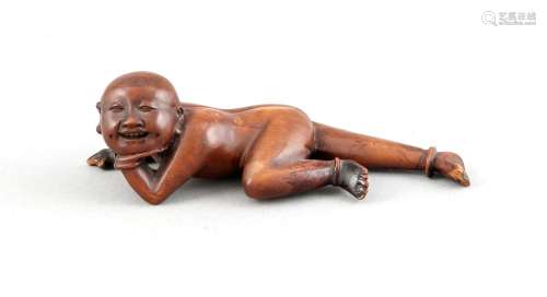Buchsbaumschnitzerei, China, 1. H. 20. Jh., liegender, nackter Mann mit aufgestütztem Kopf, fein ausgearbeitetes Gesicht mit Zähnchen und Grübchen, ein Fuß best., L. 12 cm