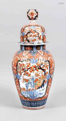 große Imari-Bodendeckelvase, Japan, Arita, 19. Jh., bauchige Form, gerippte Wandung, Glockenförmiger Deckel mit großem Knauf, üppiger Dekor in Unterglasurblau, Eisenrot und Gold mit rautenförmigen Kartuschen mit frontaler Phönixdarstellung, große Reserven mit Landschaft und Hirsch. Dekor wiederholt sich auf dem Deckel. Haarrisse im Deckel (Innen) und im Vasenboden, Chip Deckel Innenseite, H. 86 cm