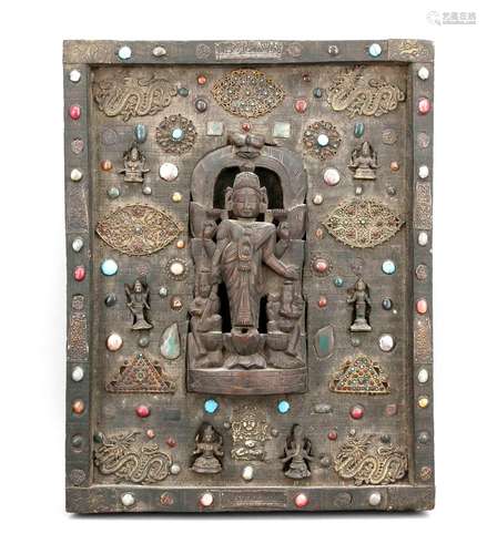 Gebetstafel, Tibet (Ladakh), Mitte 20. Jh., Holztafel mit Holzfigur im Zentrum, umgeben von kleineren Bronzefiguren, Steincabochonbesatz, 55 x 43 cm