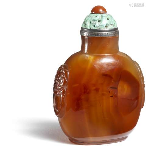 A Chinese carnelian agate snuff bottle, rectangular shaped, sides carved with mask and handles. Qianlong-Jiaqing 1740–1800. H. 8,7 cm.