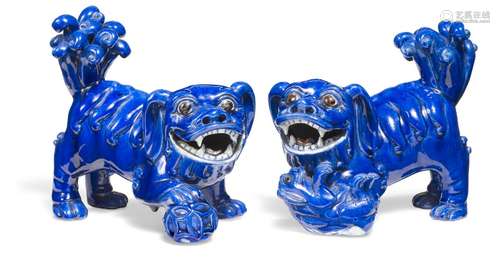 A pair of porcelain Fo-dogs in blue glaze, the he with a ball under the paw and the she with a puppy under the paw. 19th century.