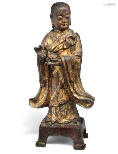 A Chinese partly gilt and lacquered bronze Buddha standing with a bowl, dressed in ruched robe on a throne. Ming, 16th c. Weight 1570 g. H. 25 cm.