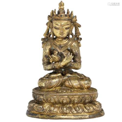 A Vajradhara buddha of gilded bronze, seated in meditating position holding bell and vajra. Tibet 17th century. H. 14.5 cm.