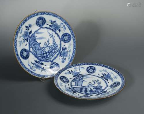 A pair of Kangxi blue and white dishes, painted with a child on the centre in a veranda within