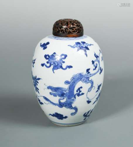 A Kangxi blue and white ovoid jar with a wooden cover, painted with two dragons amongst clouds, 15cm