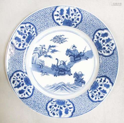 A Kangxi plate, painted with three stag hunters within six floral vignettes on the brocaded rim,