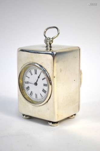 A late Victorian silver boudoir clock with circular enamel dial, hinged loop top handle and bun