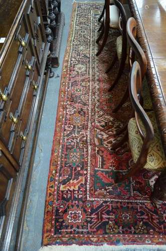 A Persian Heriz carpet with large central floral medallion on terracotts ground within guarded