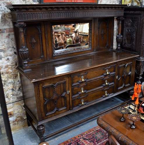 An oak mirror backed sideboard in the Carolean style, centred by three drawers flanked by cupboards,