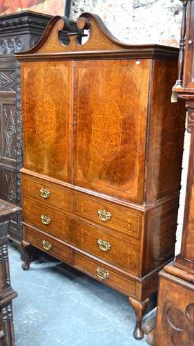 A 19th century Sheraton Revival style cabinet on stand, the broken swan neck pediment over a pair of