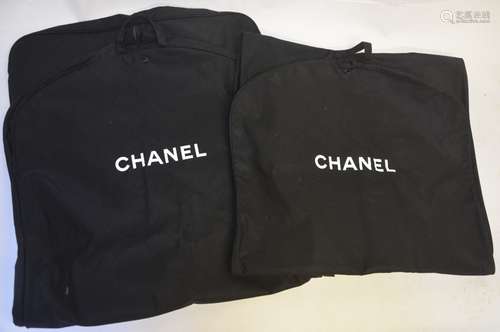 Four Chanel suit carriers contained in a Chanel retail bag with Camellia to front