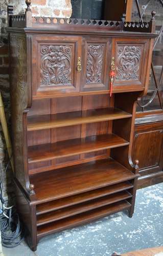 A good quality Art Nouveau period red walnut library cabinet, the fret-cut three-quarter gallery top