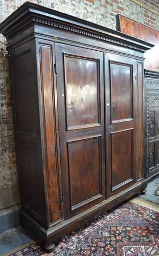 A substantial Palazzo scale Florentine fruitwood armoire, the dentil moulded canopy top over twin