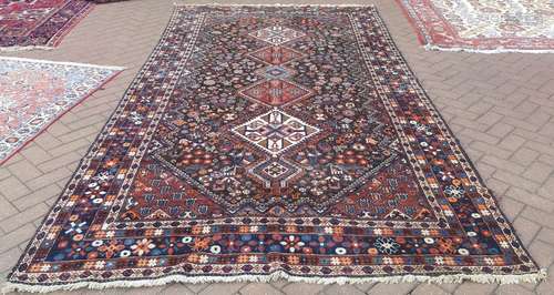 A Persian Qashqai kelleigh carpet, linked diamond medallions on dark brown field decorated with