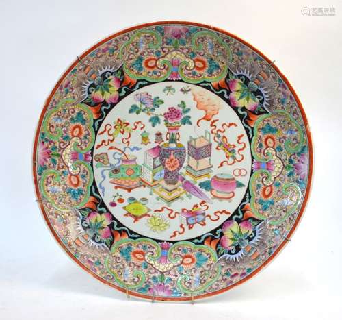 A famille rose circular dish, decorated with a central design of scholars implements and sacred